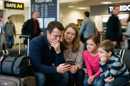 Should You Buy Travel Insurance? with family at an airport receiving bad news via cell phone.